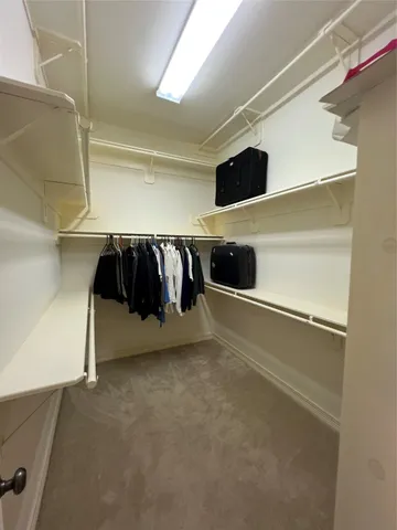 a view of walk in closet with clothes and shoes