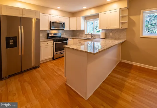 a kitchen with stainless steel appliances granite countertop a refrigerator a stove top oven a sink and dishwasher