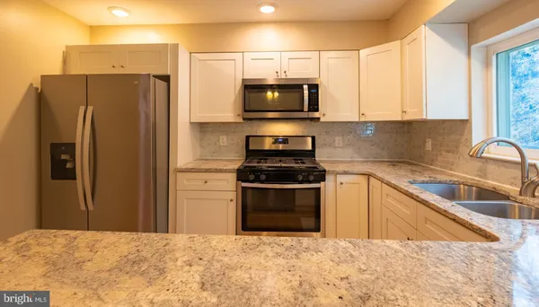 a kitchen with granite countertop a refrigerator and a sink