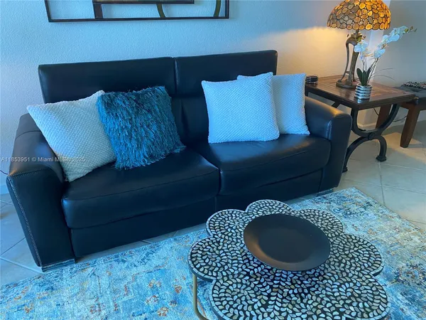 a living room with a couch wooden floor and a potted plant
