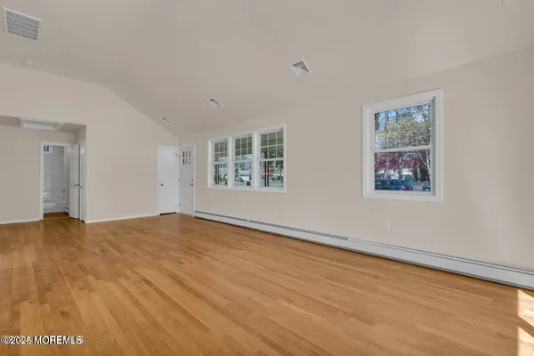 a view of an empty room with a window and wooden floor