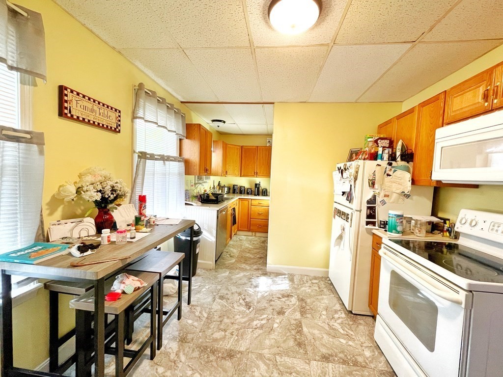 550 Eastern Avenue Lynn, MA 01902 - Photo 16 of 32 a kitchen with stainless steel appliances a stove a refrigerator and a dining table with wooden floor