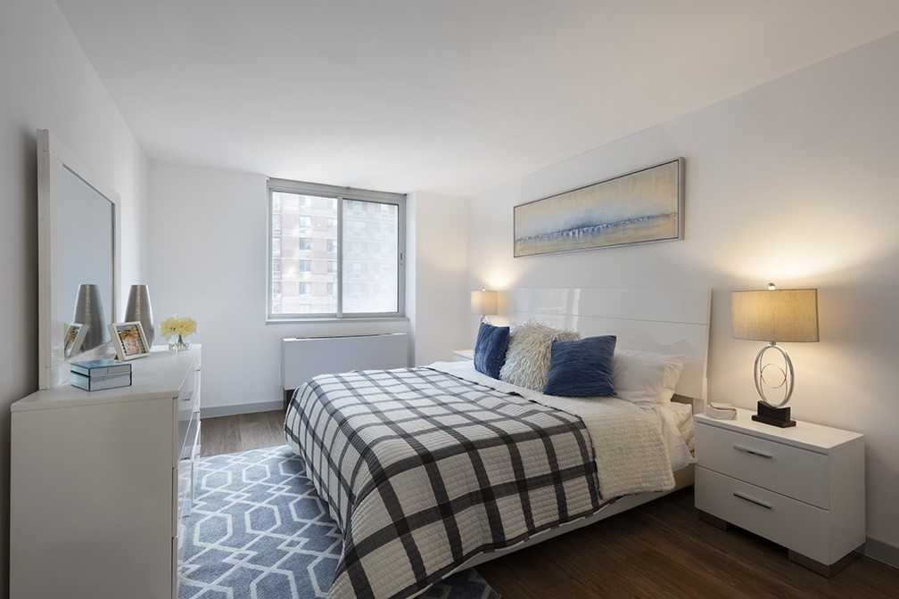 10 River Road, Unit 30007K Manhattan, NY 10044 - Photo 2 of 10 a bedroom with a bed and a lamp with window