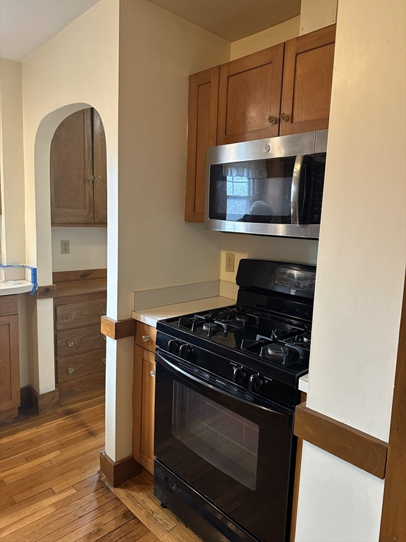 33 Amsden Street, Unit 1 Arlington, MA 02474 - Photo 7 of 18 a kitchen with granite countertop a stove and a microwave with wooden floor