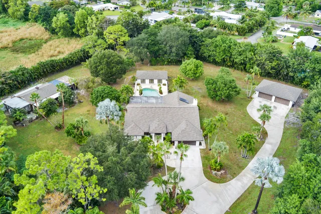 an aerial view of residential house with outdoor space and trees all around