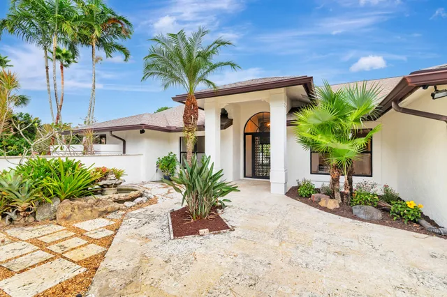 a front view of a house with a yard and palm trees