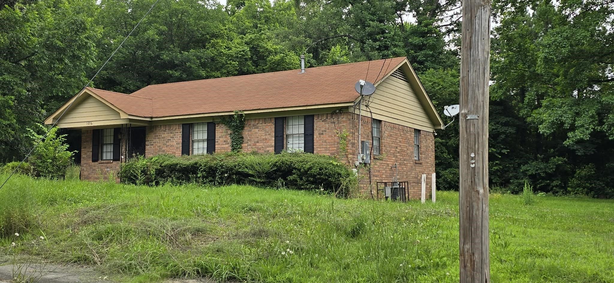 1056 Walk Road Memphis, TN 38109 - Photo 2 of 3 Brick exterior residence featuring a brown shingle roof and black louvered shutters
