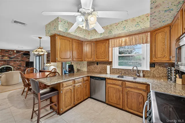 a kitchen with stainless steel appliances granite countertop a stove top oven a sink a dining table and chairs