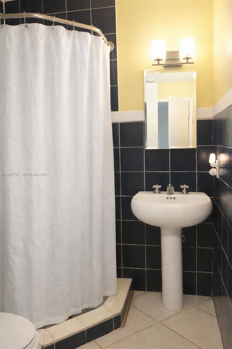 3151 Freeman Street Miami, FL 33133 - Photo 14 of 20 a bathroom with a sink a mirror a toilet and shower