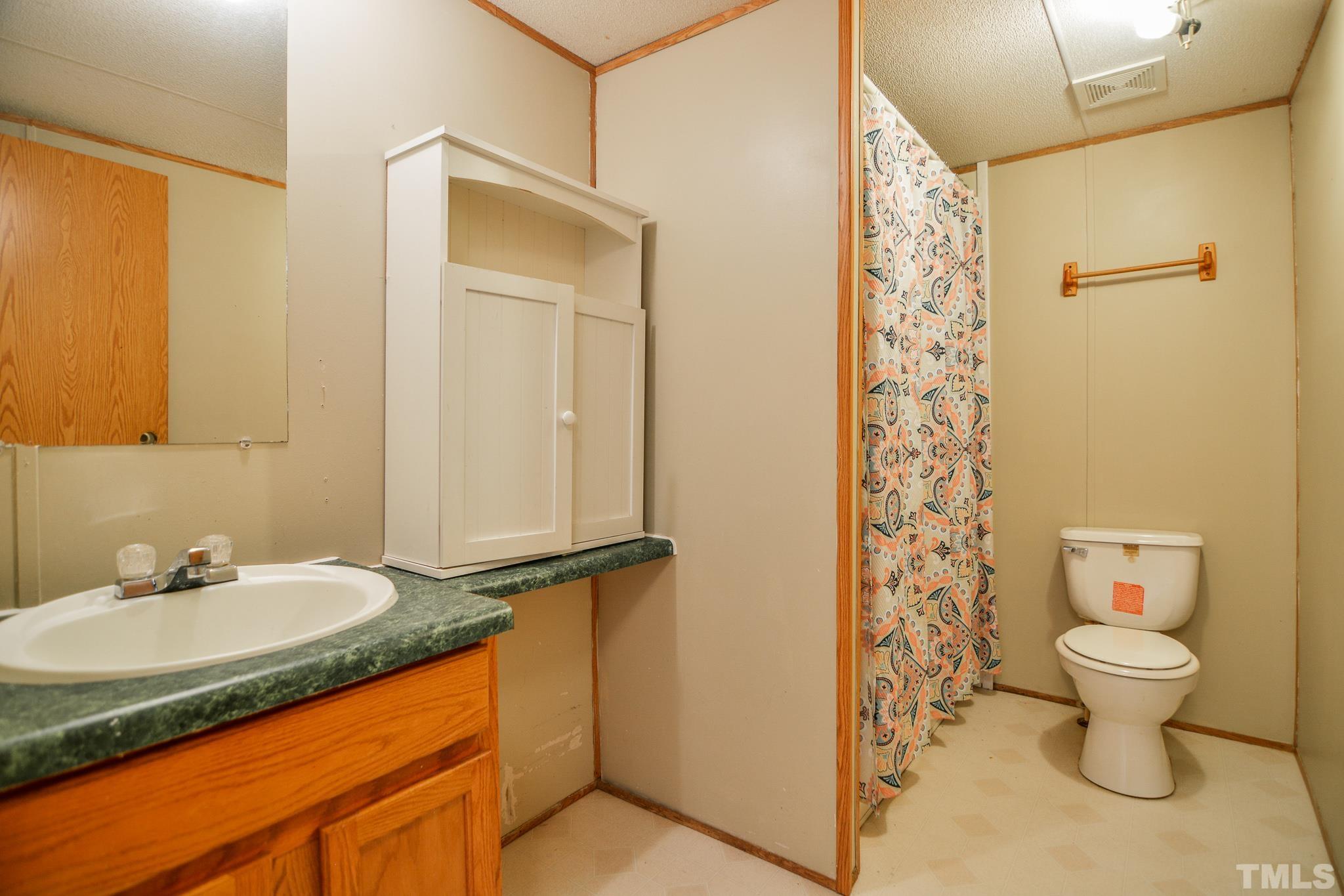 141 Wilson Road Lucama, NC 27851 - Photo 23 of 23 a bathroom with a granite countertop sink and a mirror