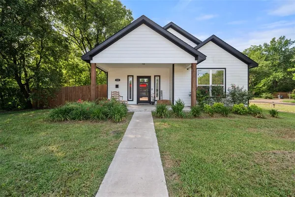 a front view of a house with a yard and potted plants