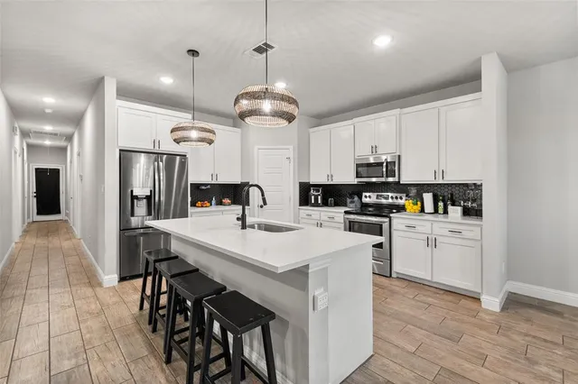 a kitchen with a dining table cabinets stainless steel appliances and a chandelier