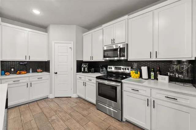 a kitchen with stainless steel appliances granite countertop a stove a sink and white cabinets