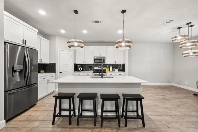 a kitchen with refrigerator and chairs