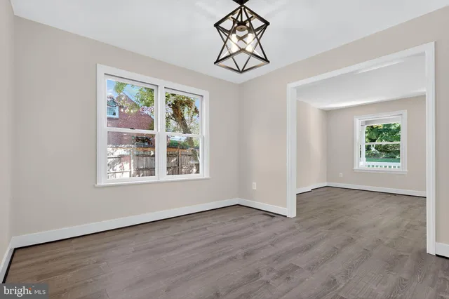 a view of an empty room with wooden floor and window