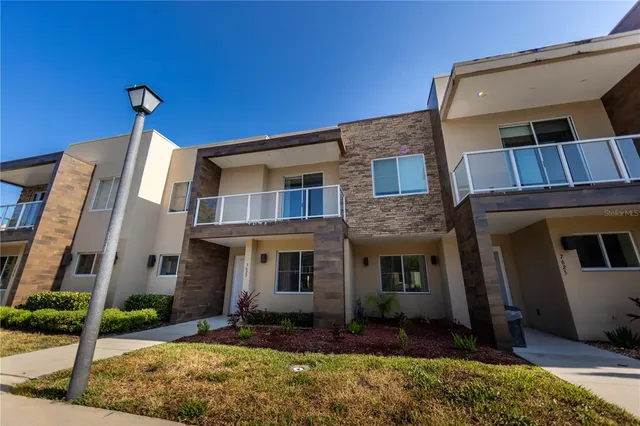 a view of a brick house with many windows next to a yard