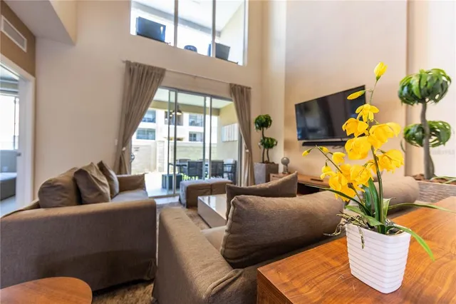 a living room with furniture floor to ceiling window and a flat screen tv