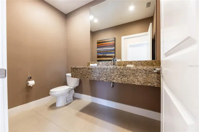 a bathroom with a granite countertop sink and a toilet