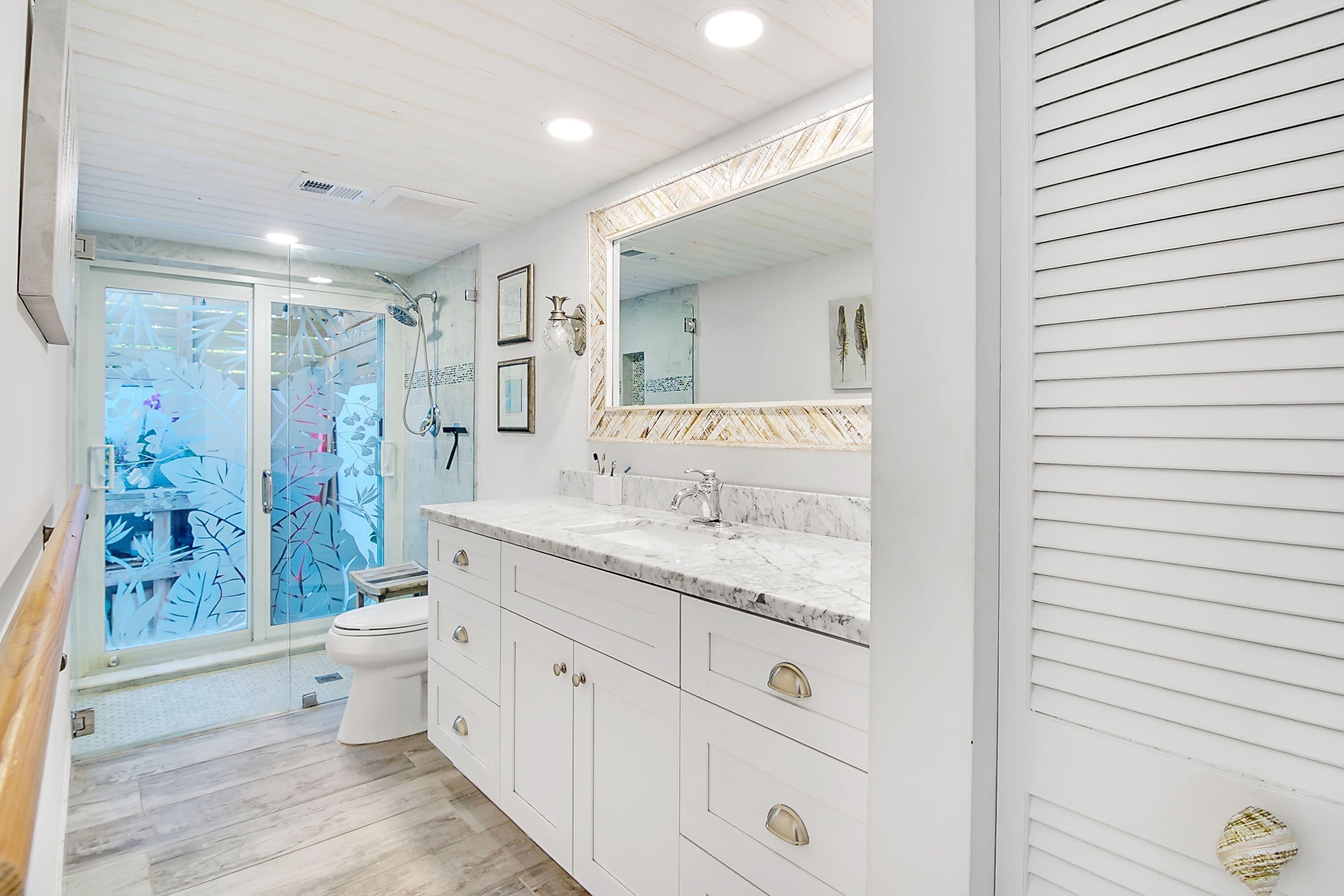 709 Irwin Lane Jupiter, FL 33458 - Photo 16 of 37 a spacious bathroom with a granite countertop sink a toilet a mirror and shower