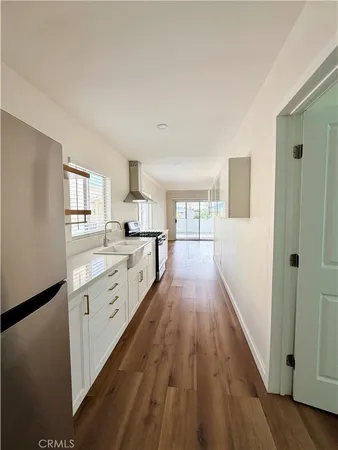 a large kitchen with cabinets wooden floor and a window