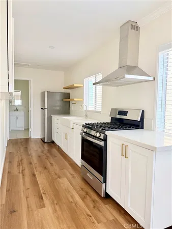 a kitchen with stainless steel appliances a stove and white cabinets