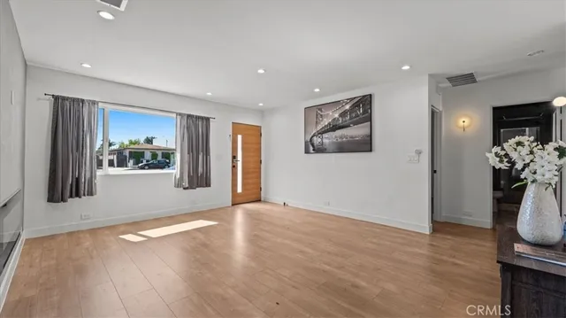 a view of an empty room with a window and wooden floor