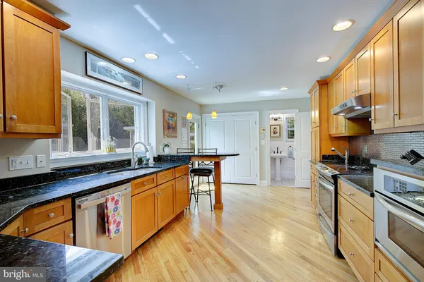 a kitchen with stainless steel appliances granite countertop sink stove top oven and cabinets