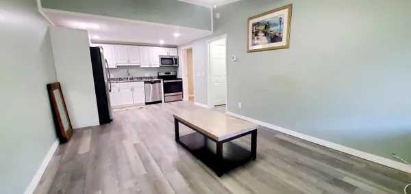 a living room with stainless steel appliances furniture a refrigerator and wooden floor