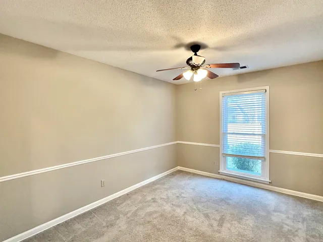 an empty room with a chandelier fan and windows
