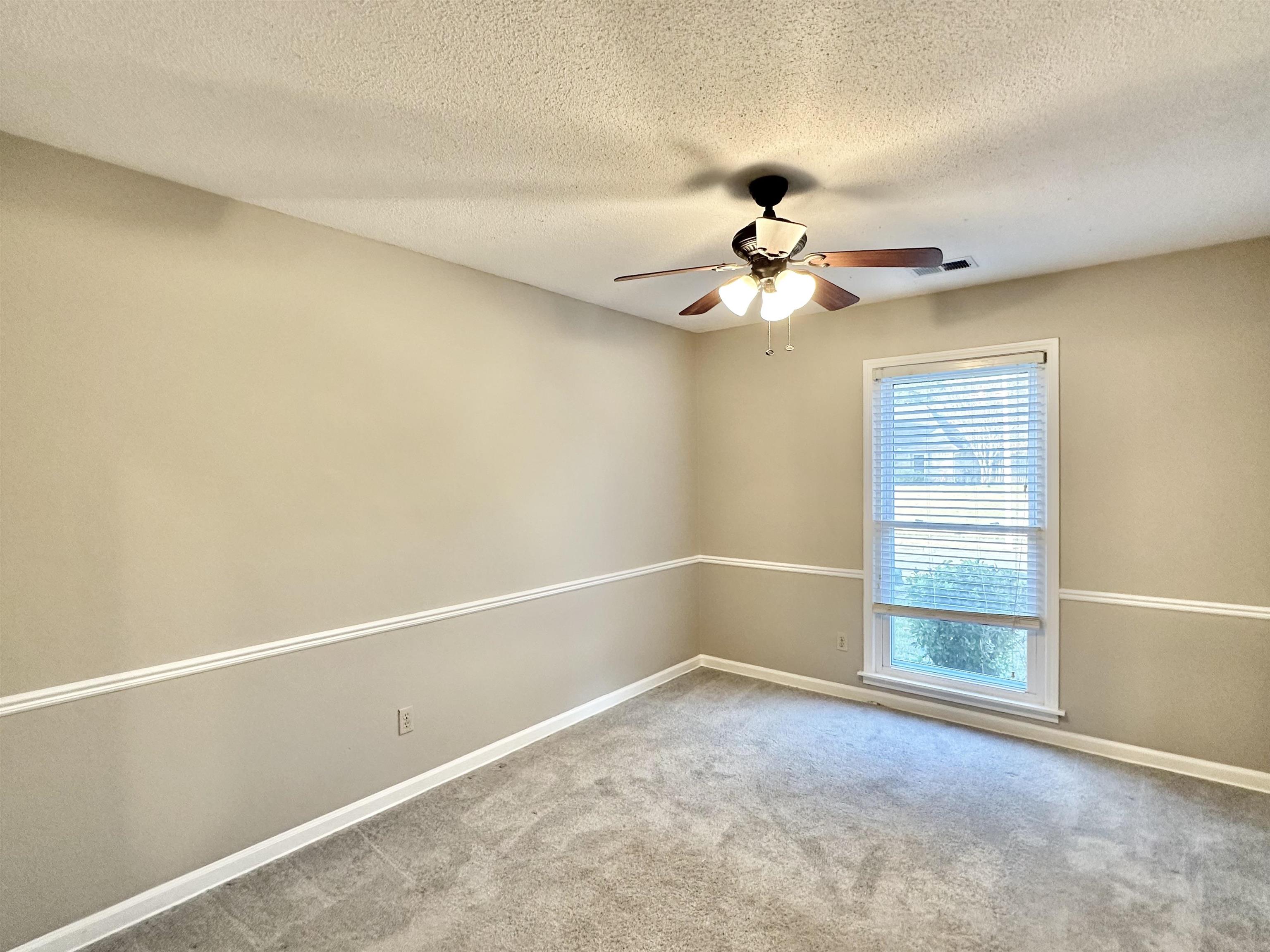 7475 Kingsland Drive Memphis, TN 38125 - Photo 15 of 32 an empty room with a chandelier fan and windows