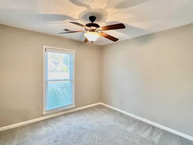 an empty room with windows and fan
