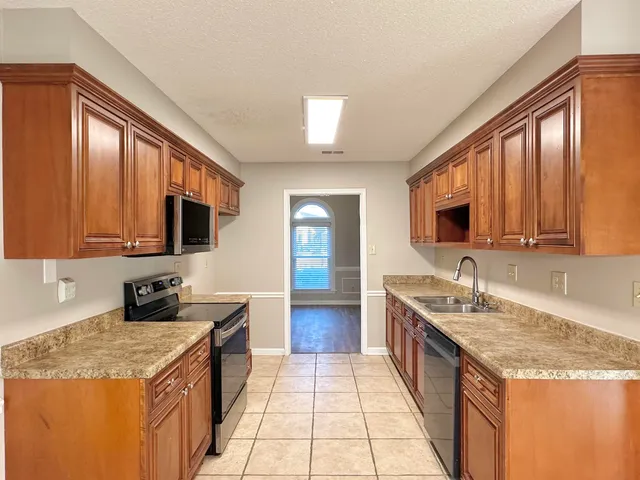 a kitchen with granite countertop stainless steel appliances a sink stove top oven and cabinets