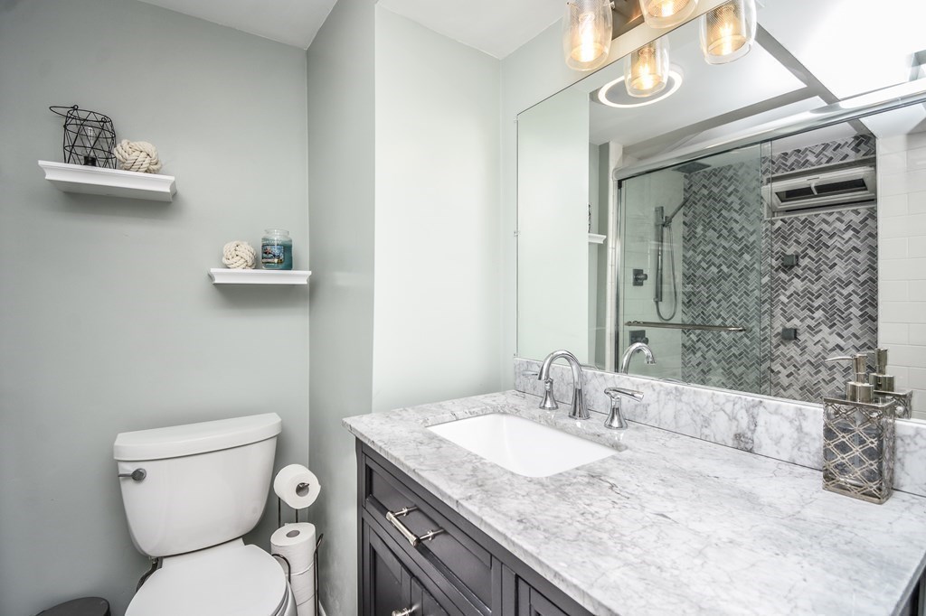 266 Bowen Street, Unit 1 Boston, MA 02127 - Photo 19 of 33 a bathroom with a granite countertop toilet a sink and a mirror