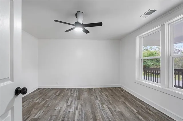 an empty room with wooden floor and windows