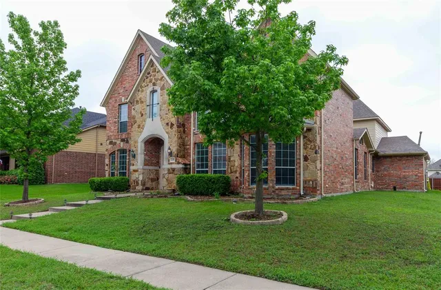 a front view of a house with garden and a tree