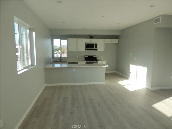 a view of a kitchen with a sink dishwasher and wooden floor