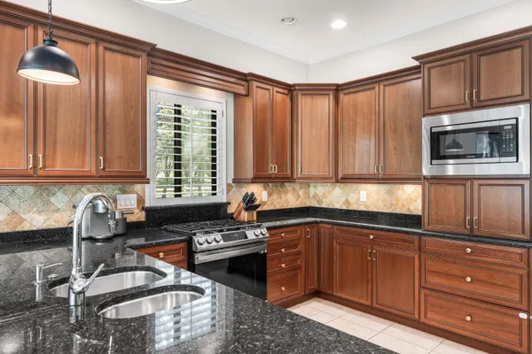 a kitchen with granite countertop a sink stainless steel appliances and cabinets