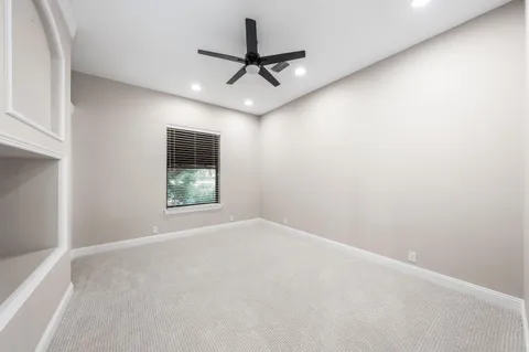 an empty room with a ceiling fan and window