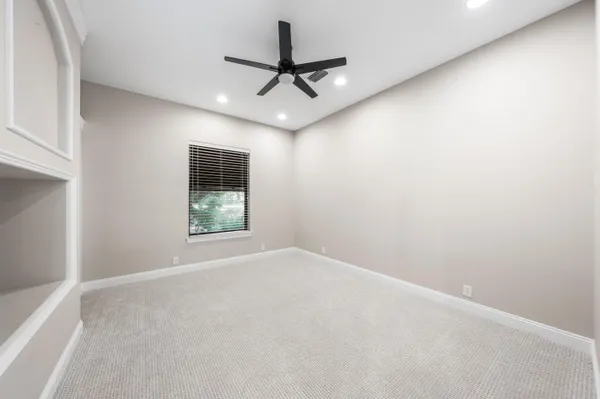 an empty room with a ceiling fan and window