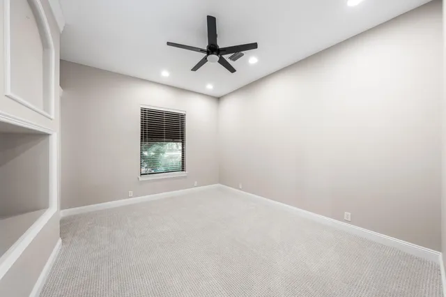 an empty room with a ceiling fan and window