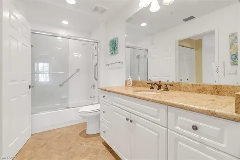 a bathroom with a granite countertop sink a toilet a mirror and shower