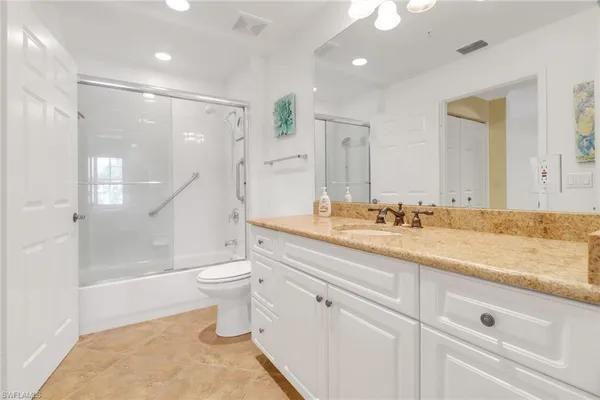 a bathroom with a granite countertop sink a toilet a mirror and shower