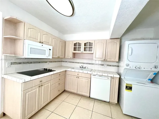 a kitchen with a sink dishwasher stove and white cabinets