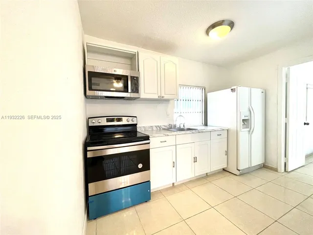 a kitchen with granite countertop white cabinets and stainless steel appliances