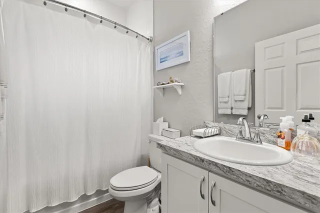 a bathroom with a granite countertop sink toilet and a mirror