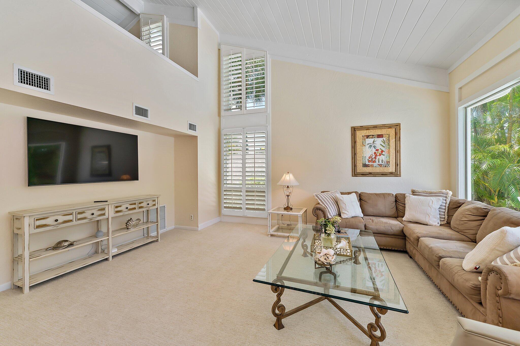 107 Mako Lane Jupiter, FL 33477 - Photo 7 of 41 a living room with furniture a flat screen tv a rug and white walls