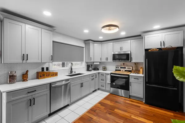 a kitchen with stainless steel appliances granite countertop a refrigerator a sink dishwasher a stove top oven and white cabinets