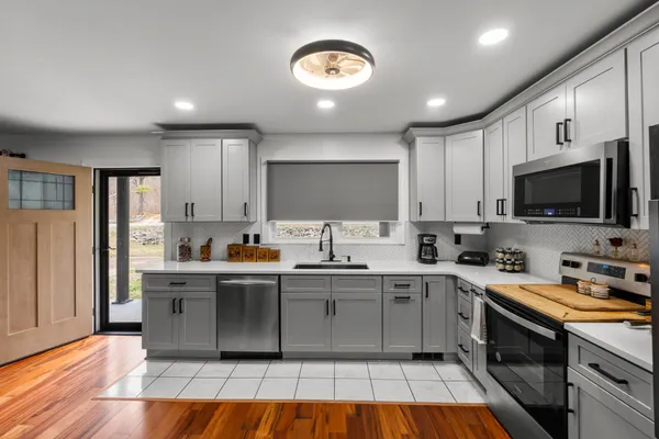 a kitchen with stainless steel appliances a sink dishwasher a stove top oven a refrigerator with island and cabinets