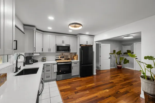 a kitchen with granite countertop a refrigerator a stove top oven a sink dishwasher and white cabinets with wooden floor