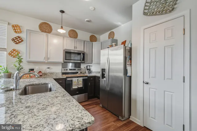 a kitchen with granite countertop a sink stainless steel appliances and a counter space